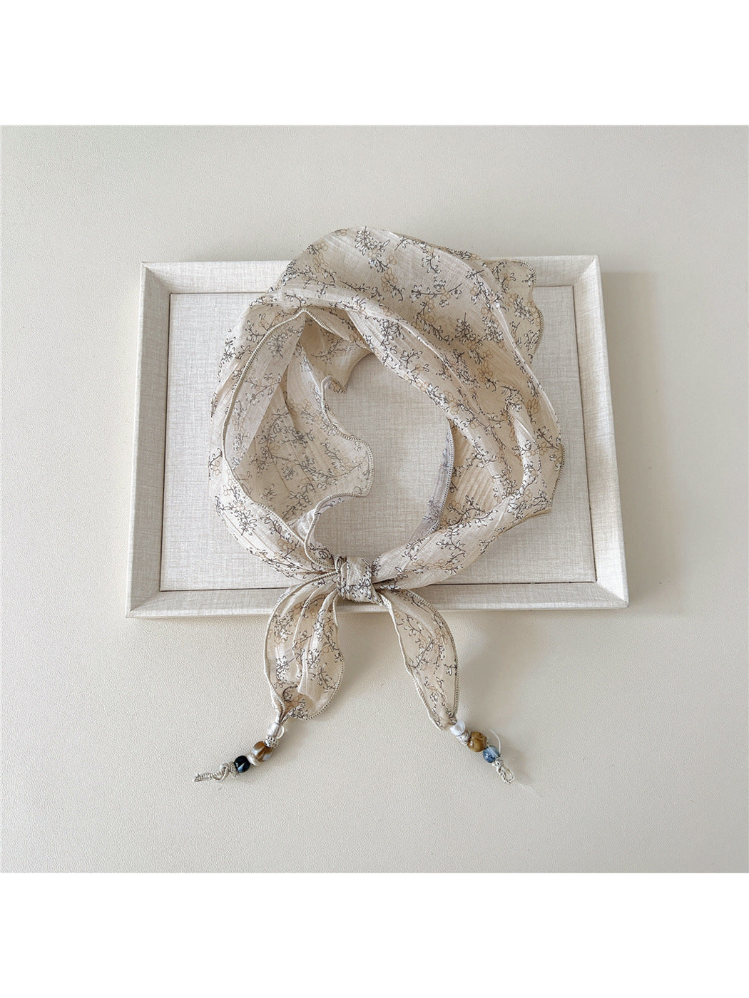 Beige Botanical triangular scarf tied with beaded tips