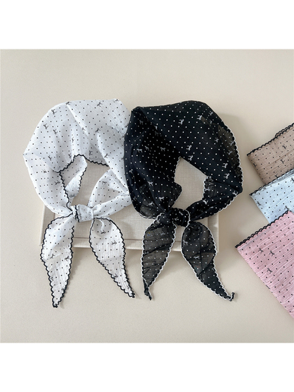 White and black patterned triangle scarves tied beside folded color options