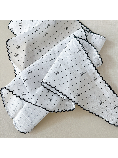 Close-up of the polka-dot and bow pattern, crinkled texture and scalloped edging