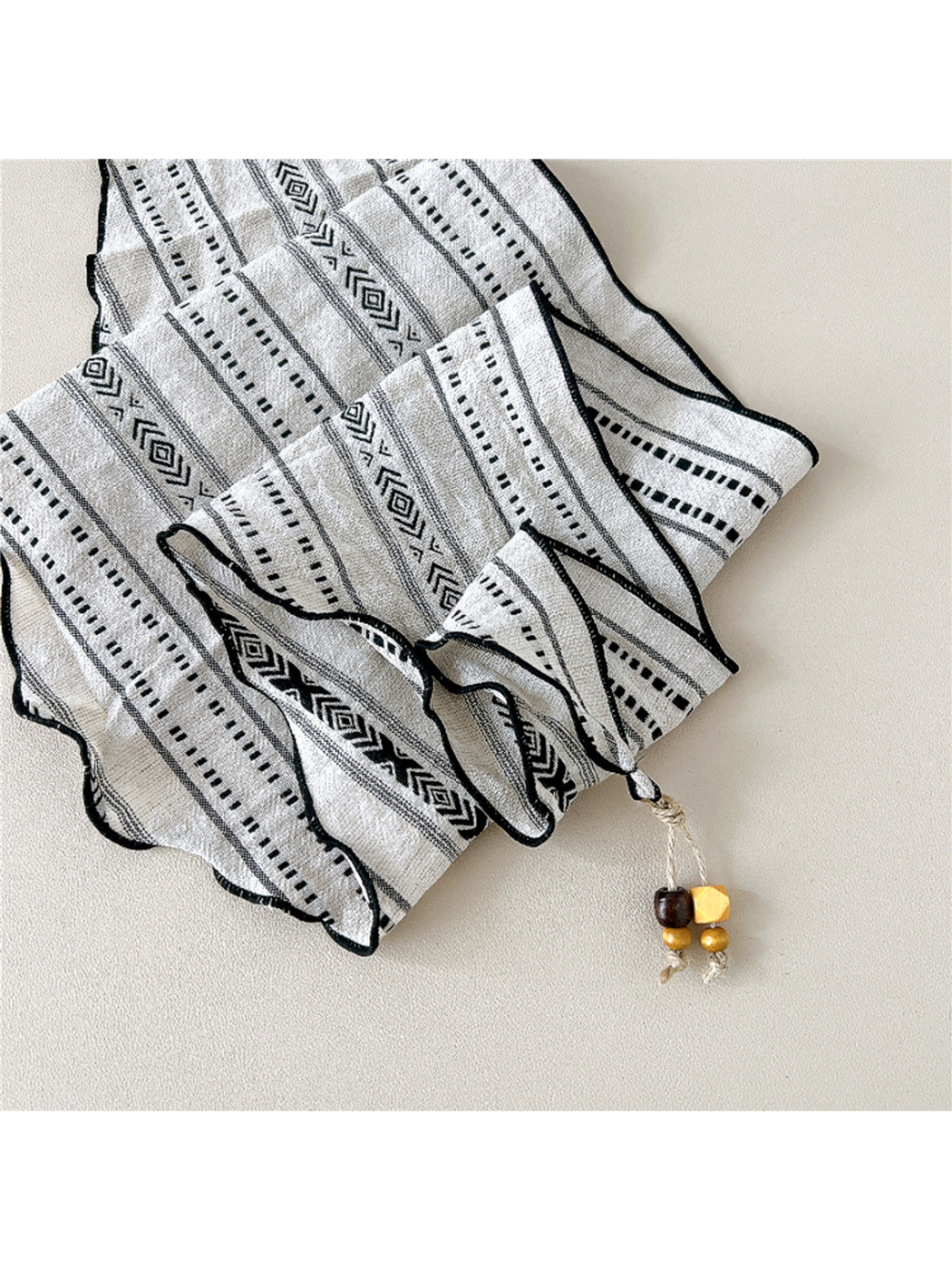 Close-up of geometric pattern, stitched edging and bead-tipped end