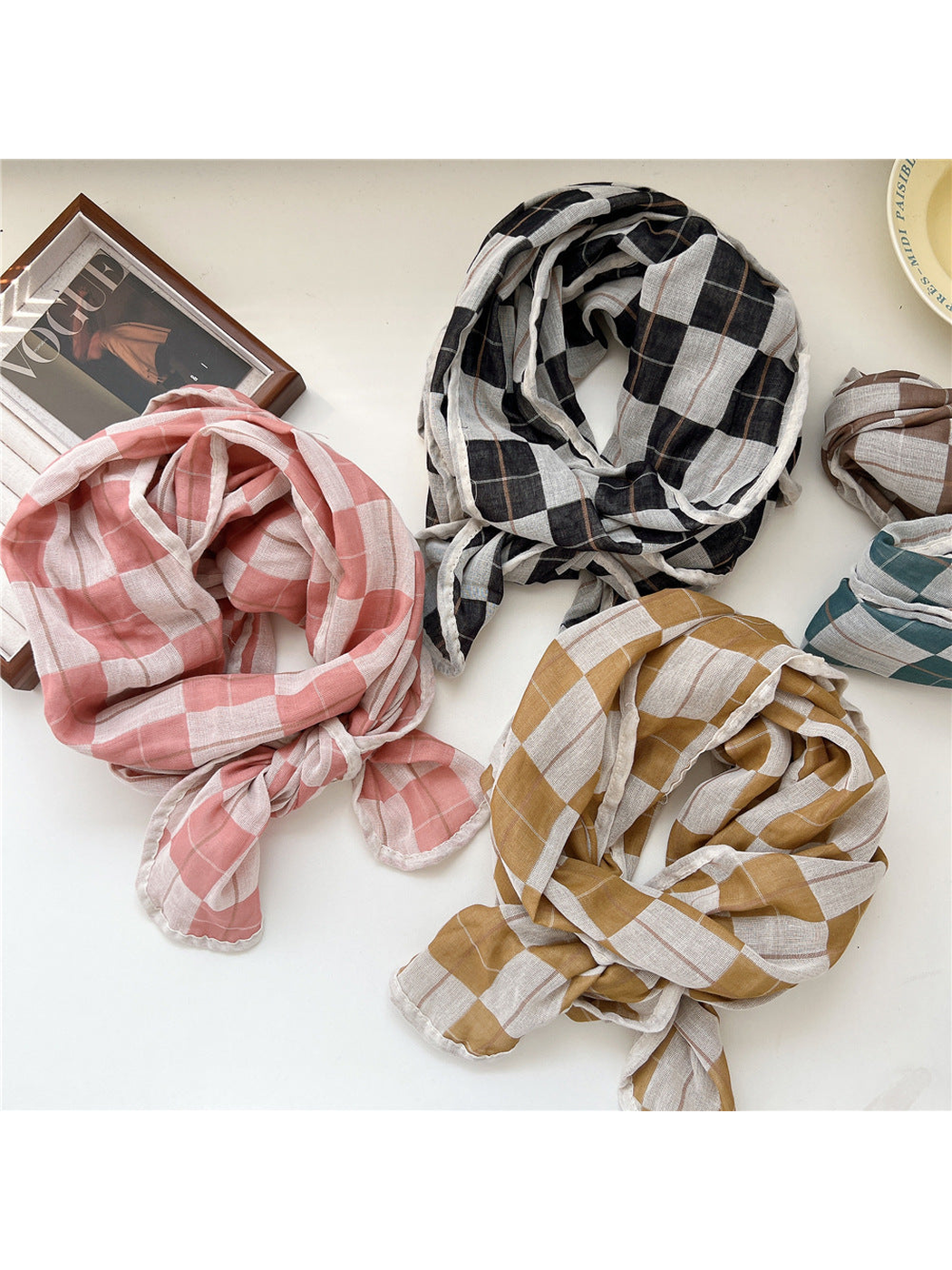 Pink, black, yellow, brown and turquoise plaid scarves arranged on a tabletop