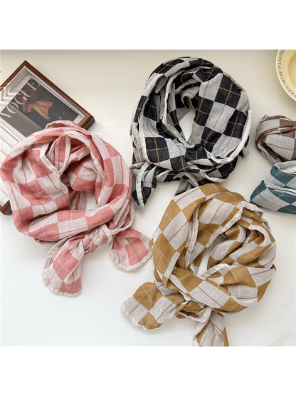 Pink, black, yellow, brown and turquoise plaid scarves arranged on a tabletop