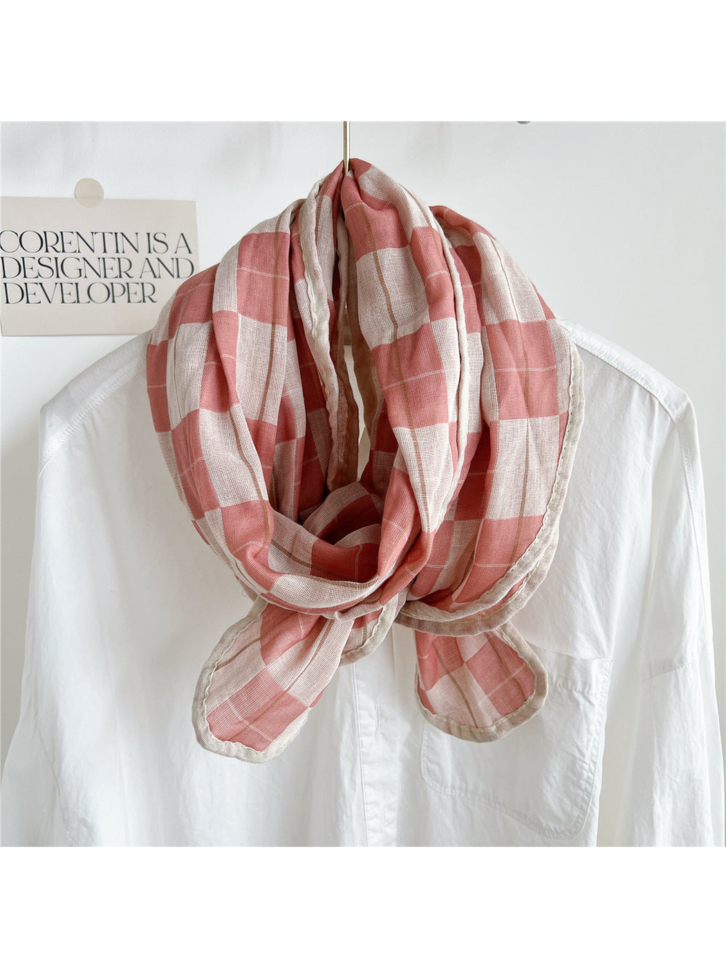 Pink plaid scarf draped over a white shirt