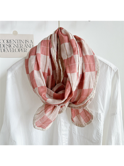 Pink plaid scarf draped over a white shirt