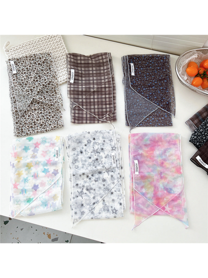 Multiple long narrow scarf styles displayed folded in a flat lay