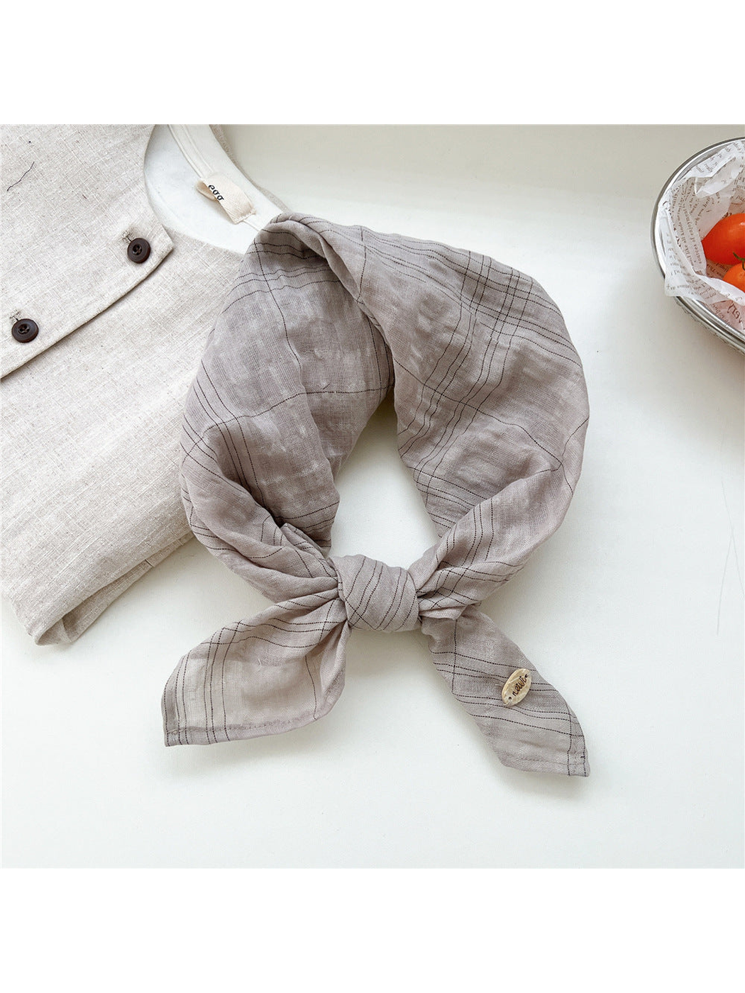 Greige fine-line plaid scarf tied in a loop
