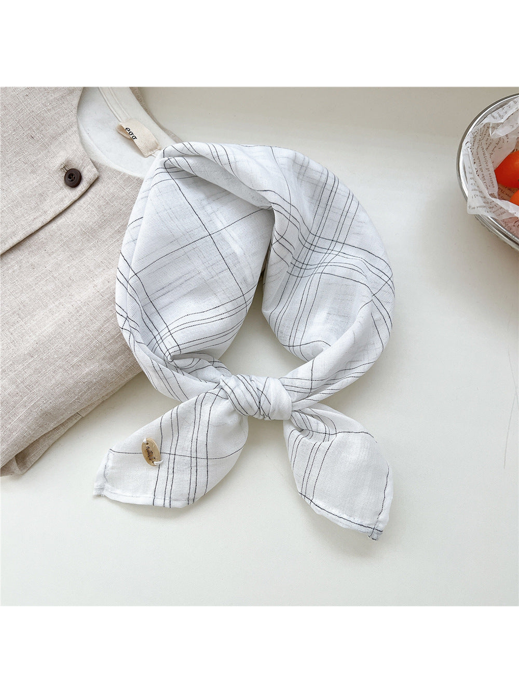 White fine-line plaid scarf tied in a loop