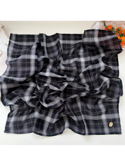 Black and gray plaid scarf spread to show its semi-sheer texture