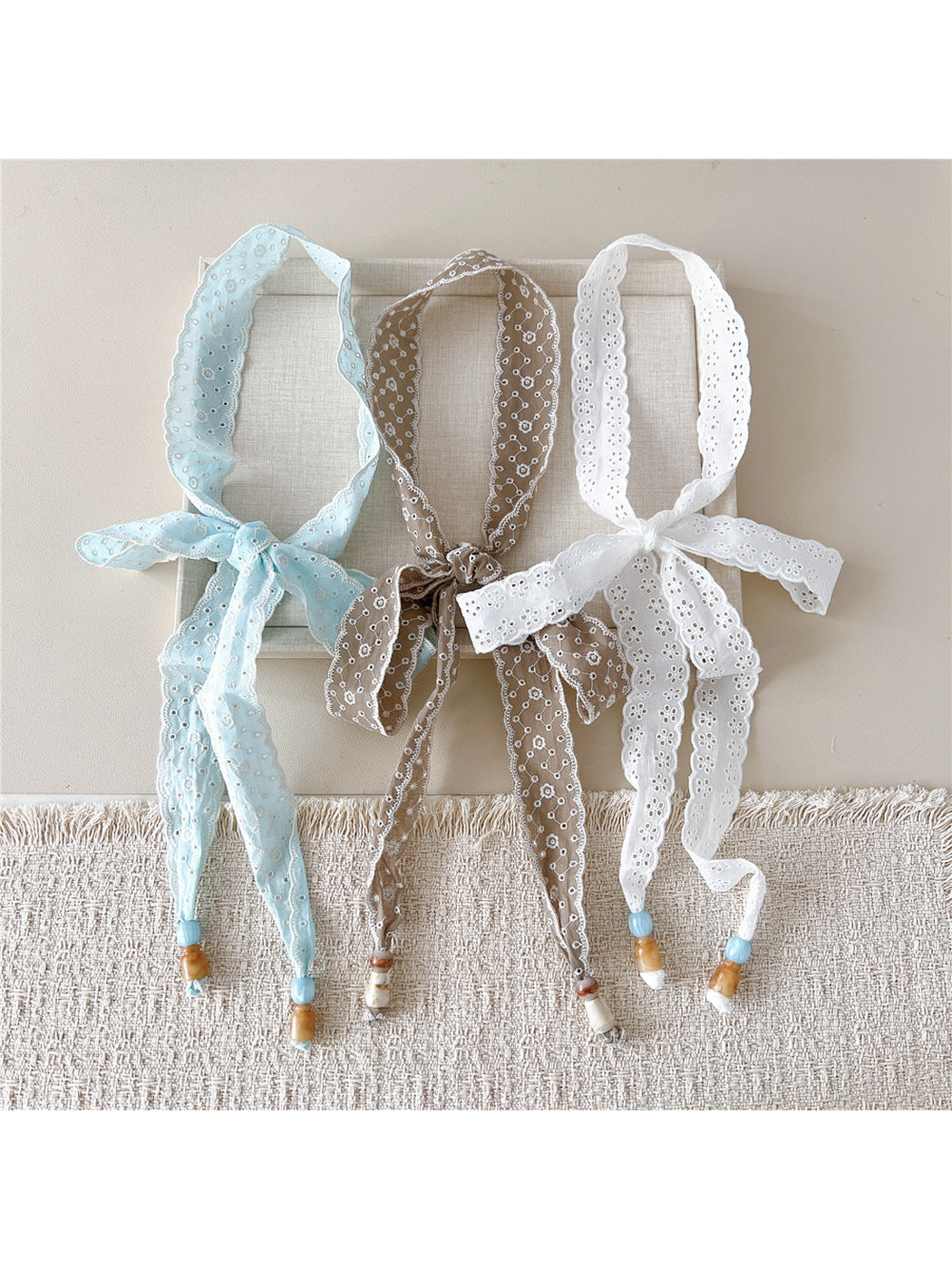 Light blue, brown and white eyelet skinny scarves displayed together