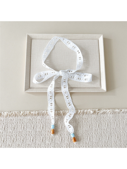 White Oval Eyelet skinny scarf tied in a bow with beaded ends