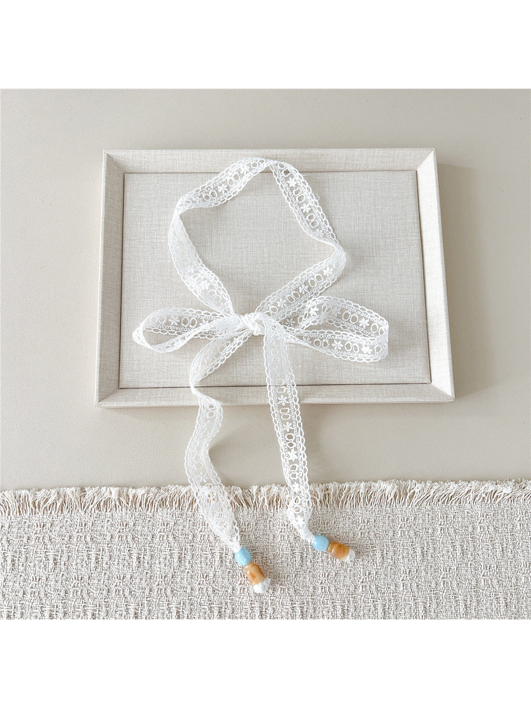 White Geometric Eyelet skinny scarf tied in a bow with beaded ends