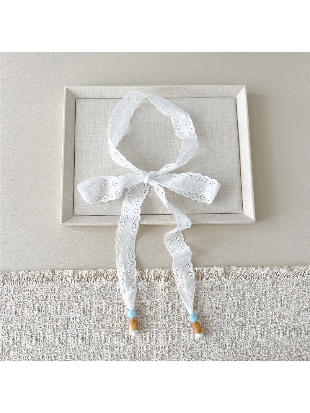 White Eyelet Flower skinny scarf tied in a bow with beaded ends