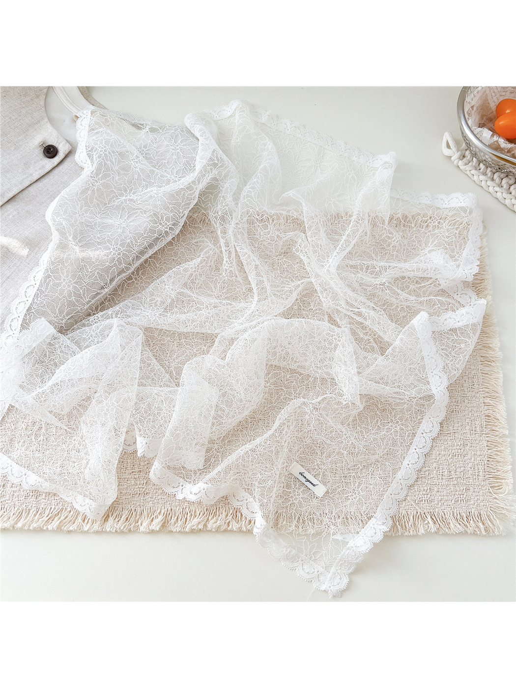 White lace scarf spread out to show the fine floral pattern and scalloped border