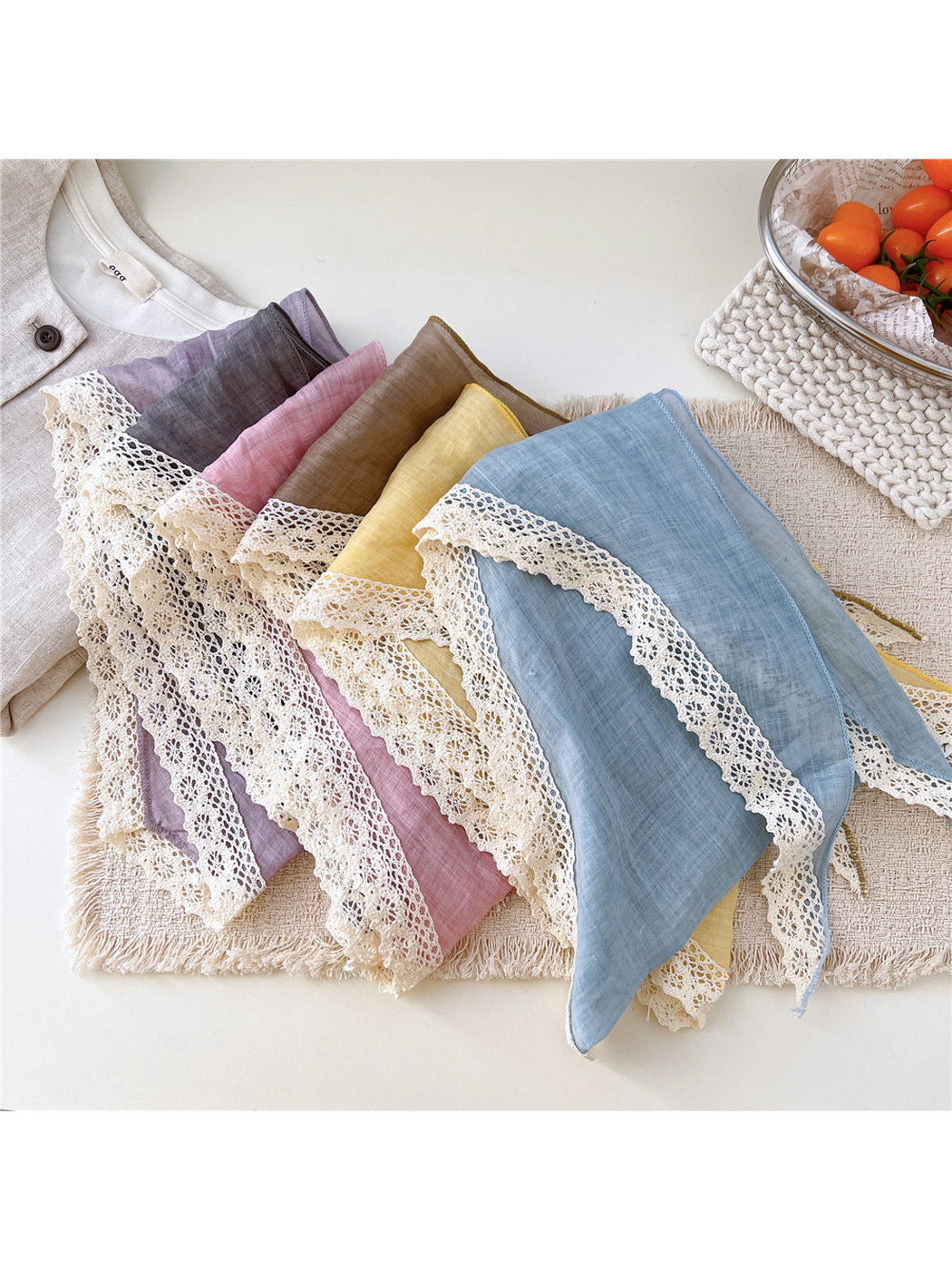 Multiple color variants of the triangle scarf arranged to show the cream lace edging