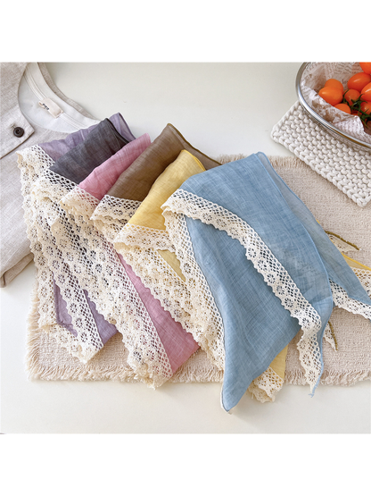 Multiple color variants of the triangle scarf arranged to show the cream lace edging