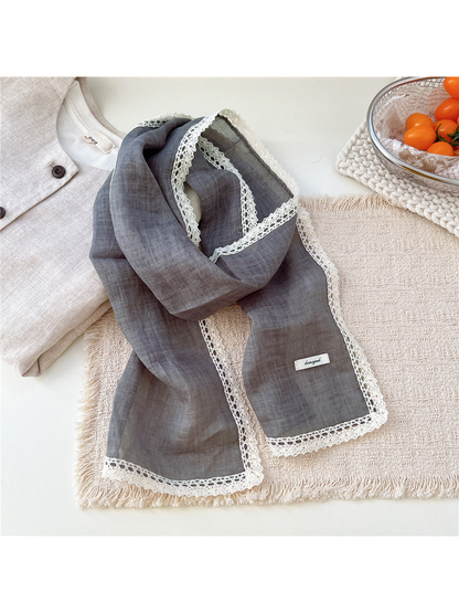Gray scarf draped on a textured neutral surface