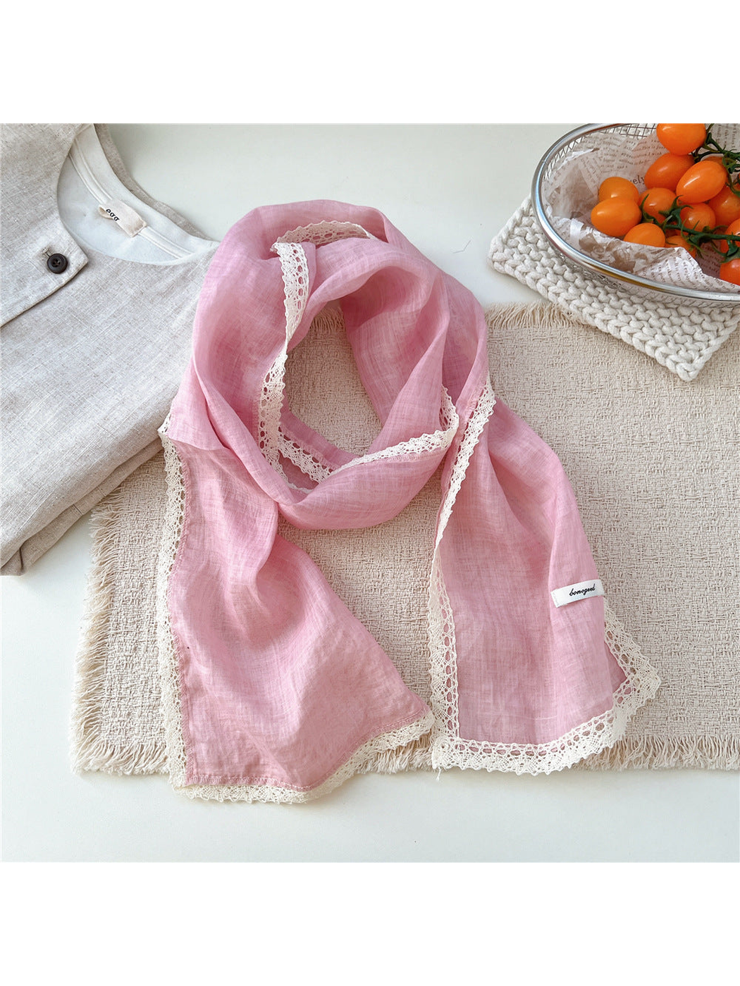 Pink scarf draped on a textured neutral surface