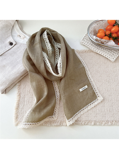 Muted green scarf draped on a textured neutral surface
