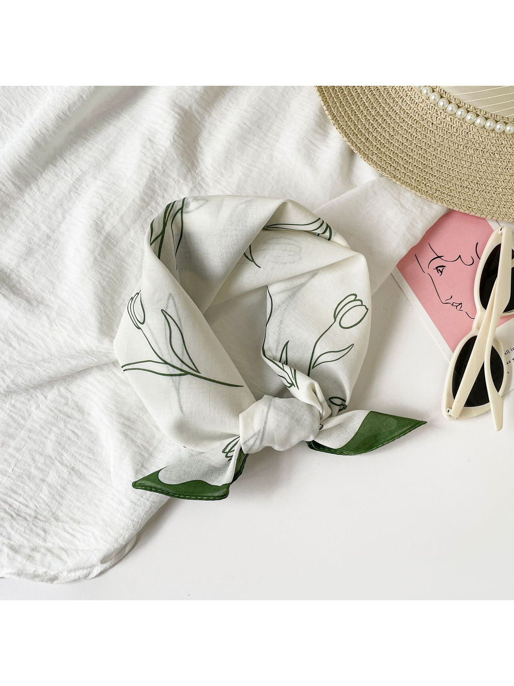 Green floral square scarf tied on a light tabletop