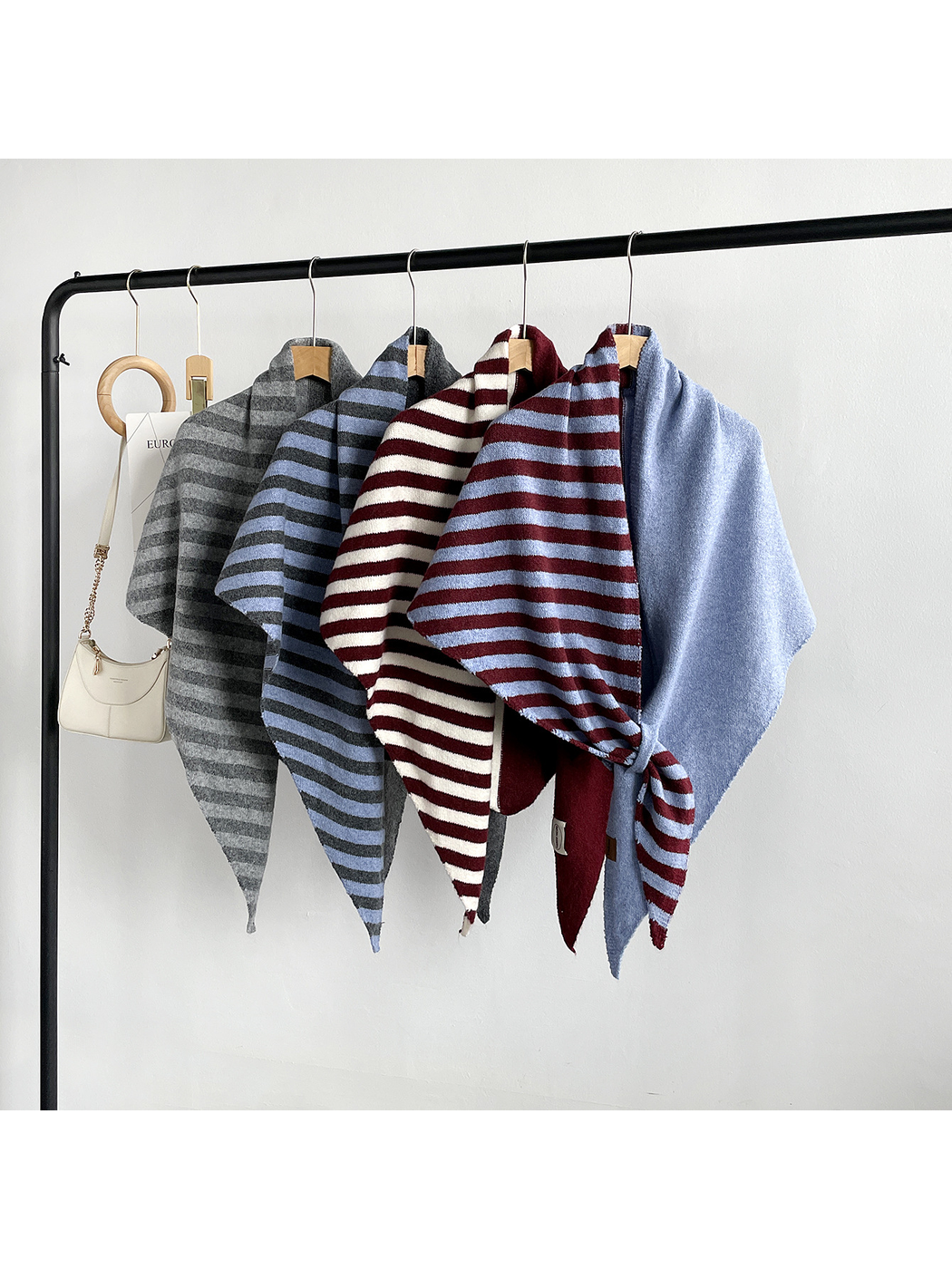 Multiple striped and solid color-block scarf styles displayed on a clothing rack
