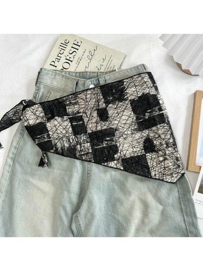 Black abstract mesh scarf spread across light-wash jeans