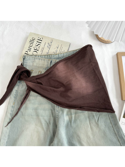Brown tonal scarf styled over light-wash jeans