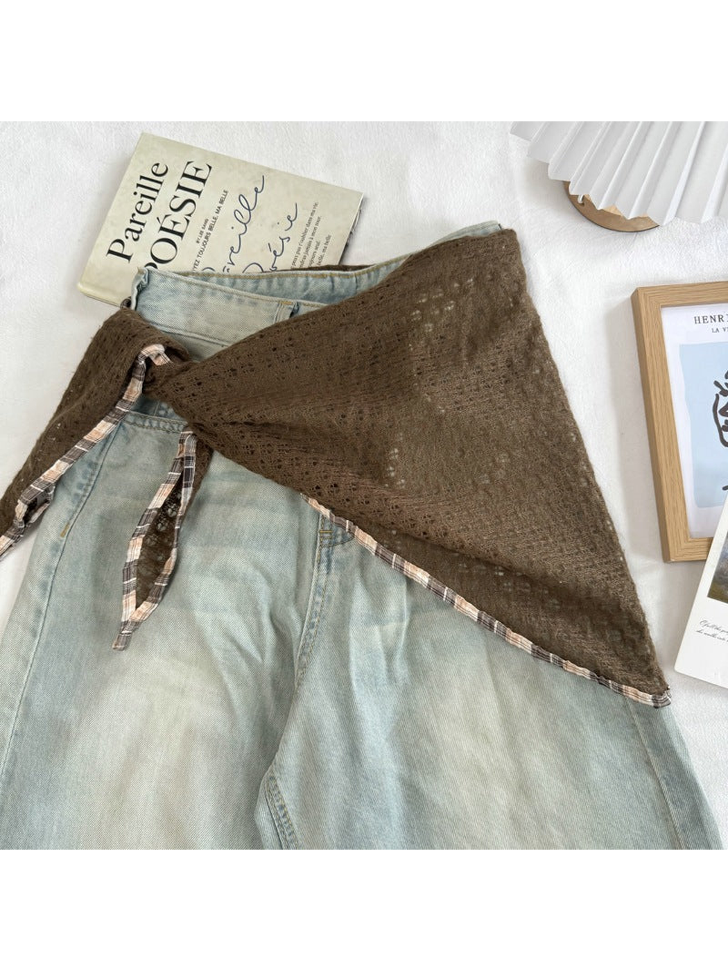 Coffee openwork scarf tied around light-wash jeans