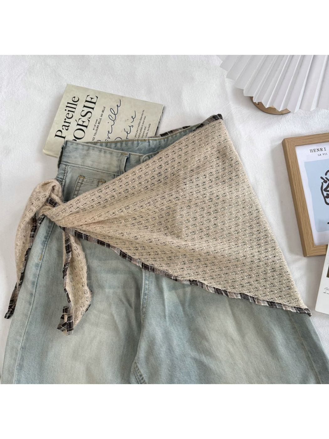 Beige openwork scarf tied around light-wash jeans
