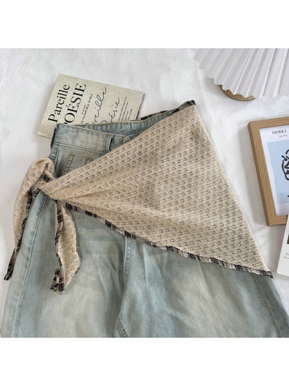 Beige openwork scarf tied around light-wash jeans