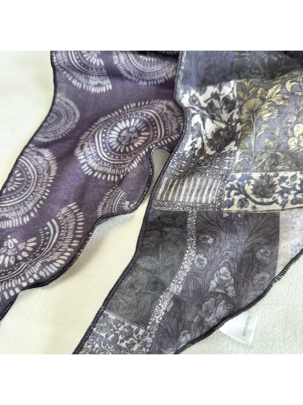 Close-up of dark gray medallion print, floral patchwork and rolled edges