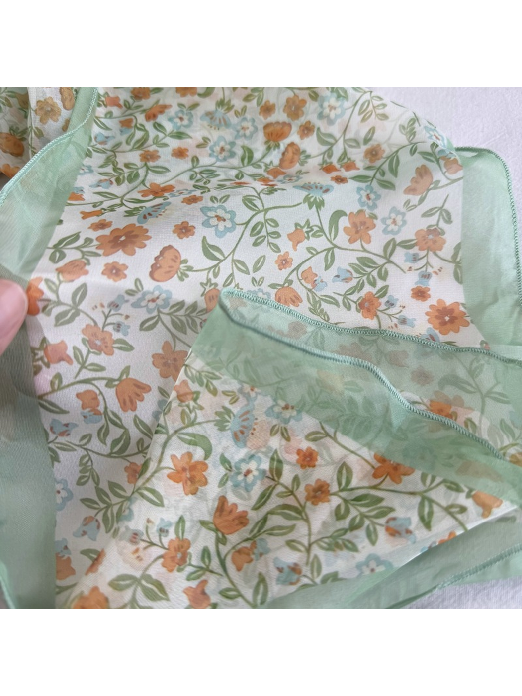 Close-up of the Mint Floral scarf pattern, sheer border and stitched edge