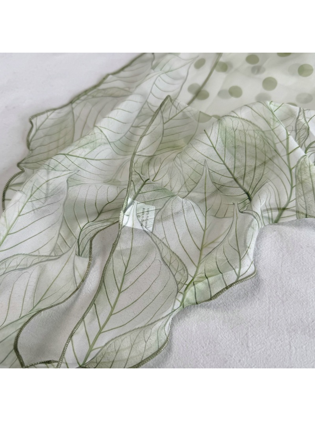 Close-up of the Green Leaves scarf with polka dots, outlined leaves and stitched edge