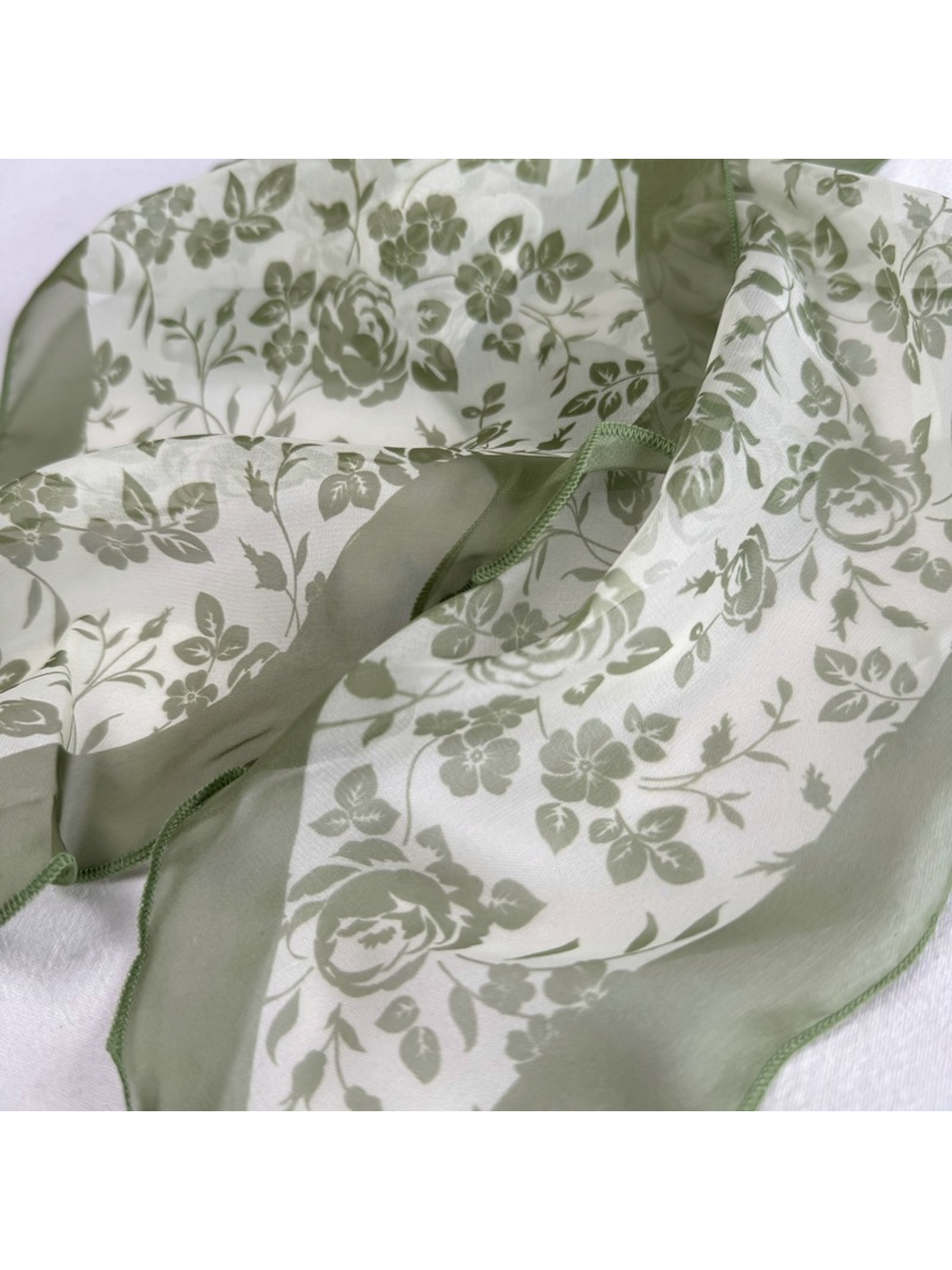 Close-up of the green rose-and-leaf print and stitched edging