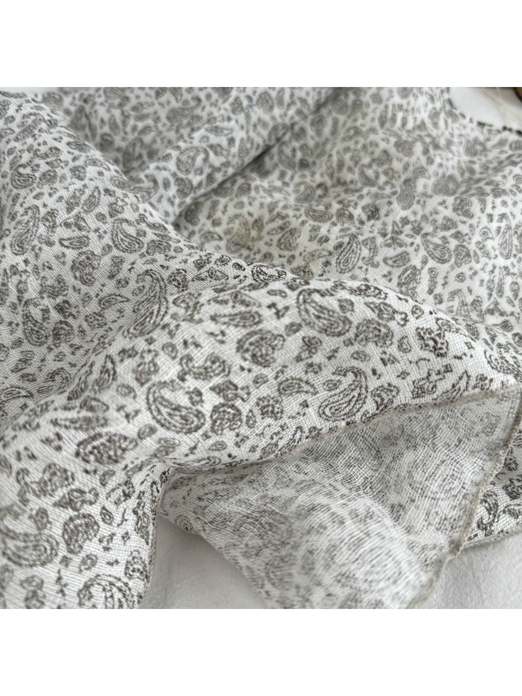 Close-up of the fine gray paisley pattern and stitched scarf edge