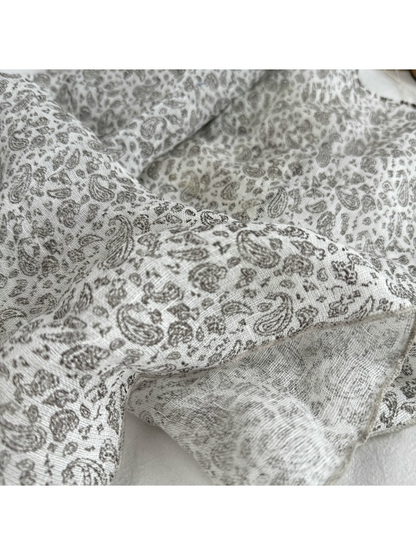 Close-up of the fine gray paisley pattern and stitched scarf edge