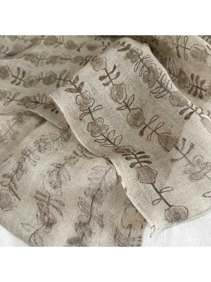 Close-up of the taupe floral stem pattern and stitched scarf edge