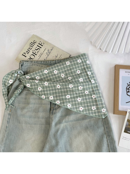 Green plaid scarf tied around the waist of pale green jeans