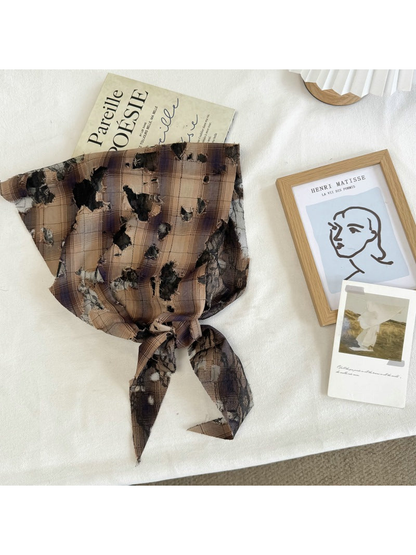 Brown plaid scarf with black mesh and frayed cutout accents, tied view