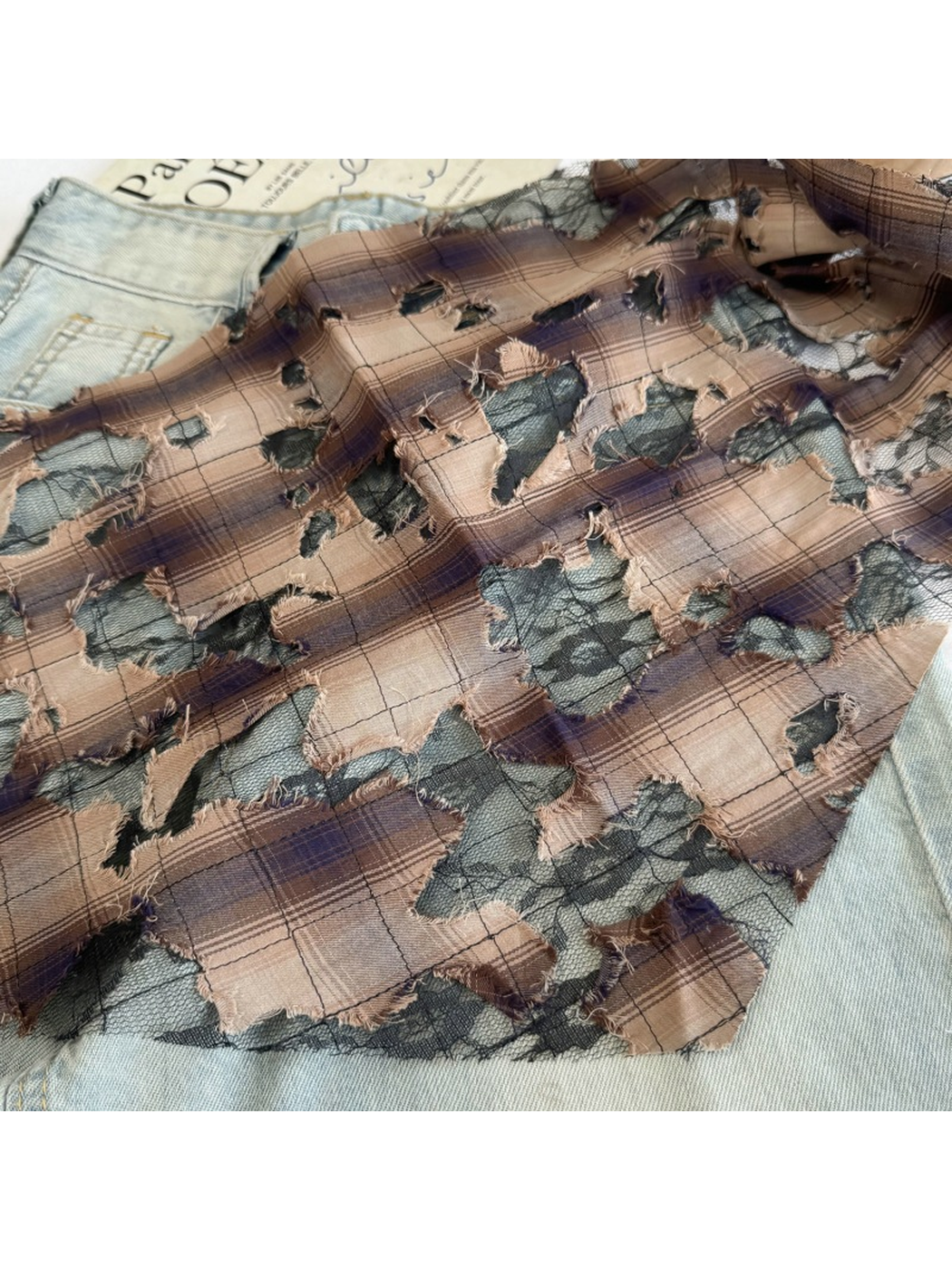 Close-up of Brown plaid with black mesh and frayed cutout details