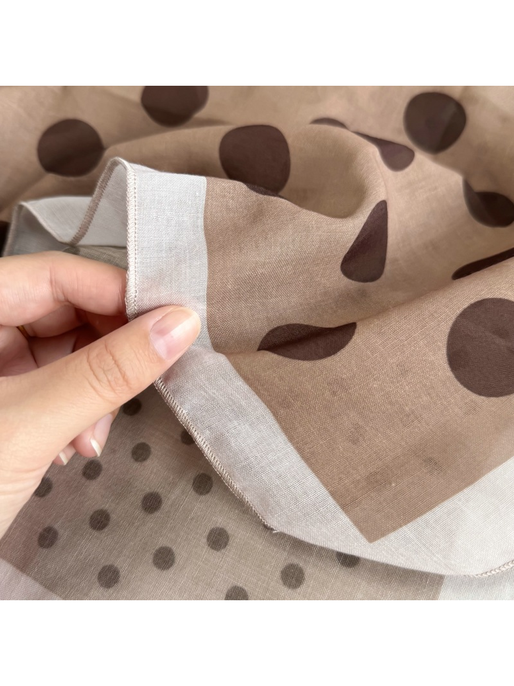 Close-up of the Beige Dots scarf border, sheer surface and stitched edge