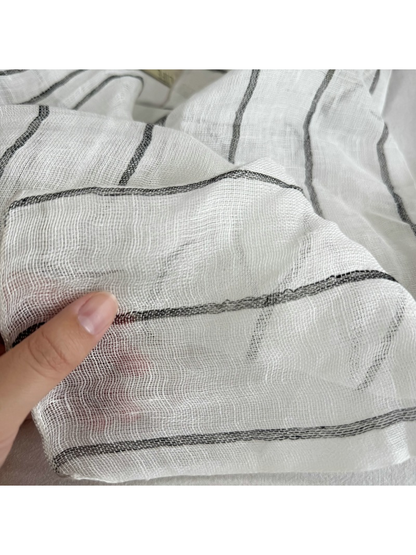 Close-up of the Gray Stripe scarf showing its semi-sheer weave and stitched edge