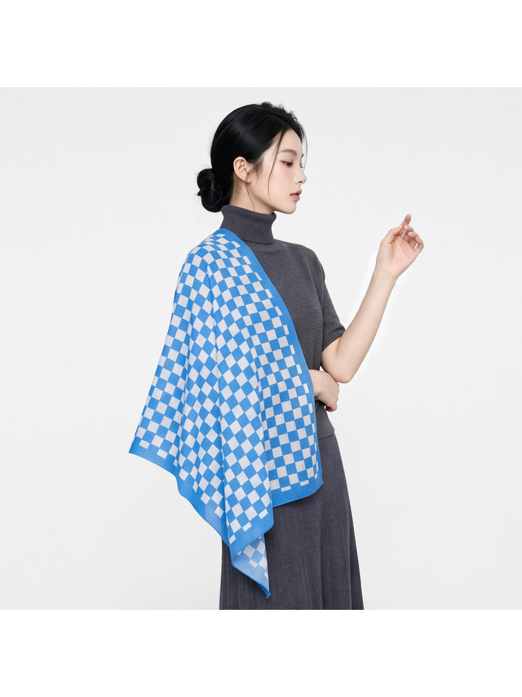 Checkerboard scarf draped over the shoulder with a gray outfit