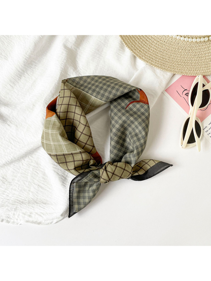 Patchwork plaid scarf tied in a loop beside a hat and sunglasses