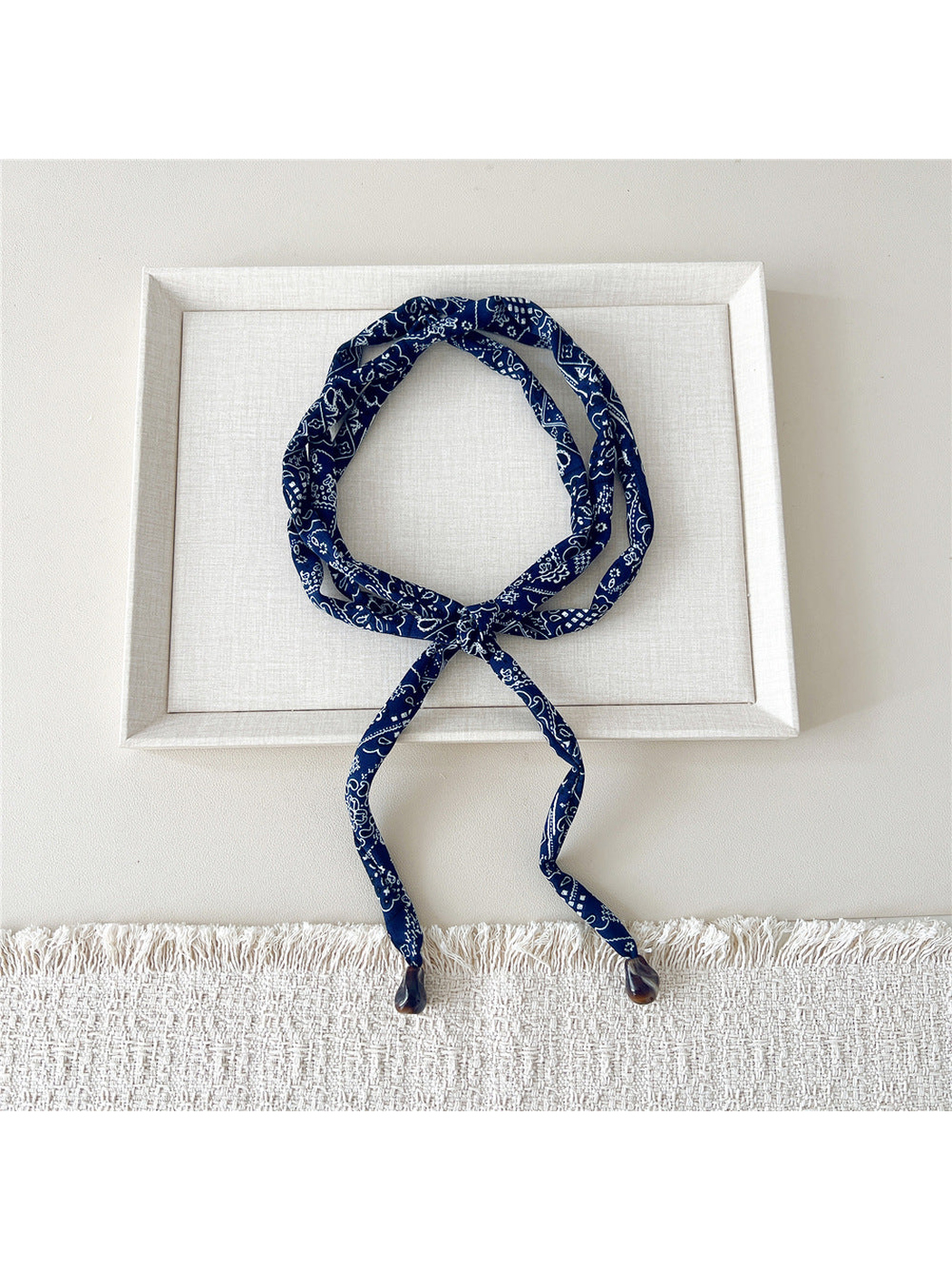 Navy paisley skinny scarf with brown teardrop accents, looped and tied
