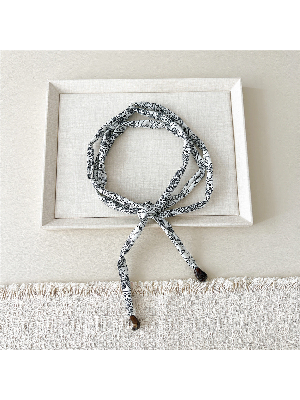 White paisley skinny scarf with brown teardrop accents, looped and tied