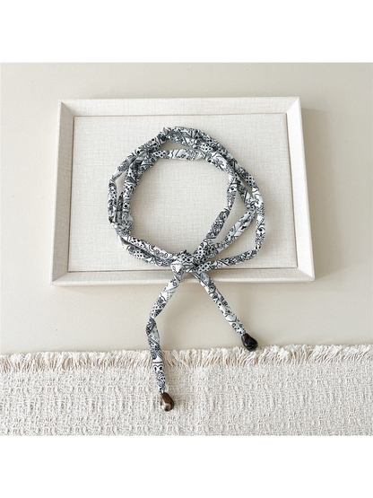 White paisley skinny scarf with brown teardrop accents, looped and tied