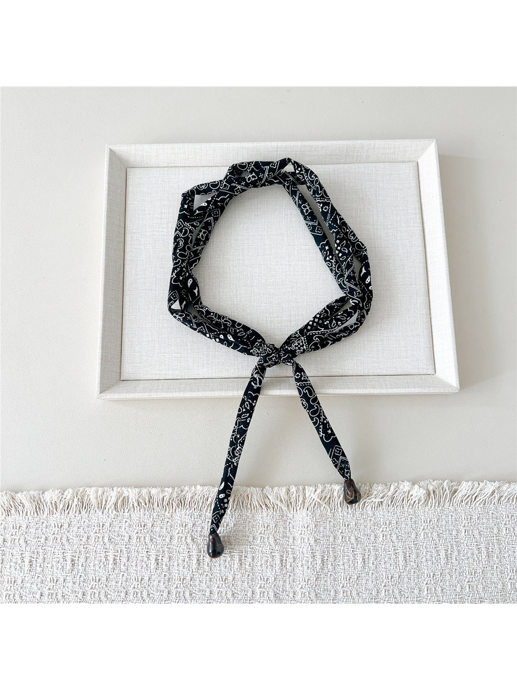 Black paisley skinny scarf with brown teardrop accents, looped and tied