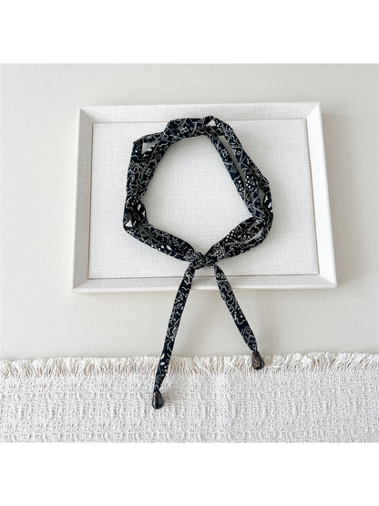 Black paisley skinny scarf with brown teardrop accents, looped and tied