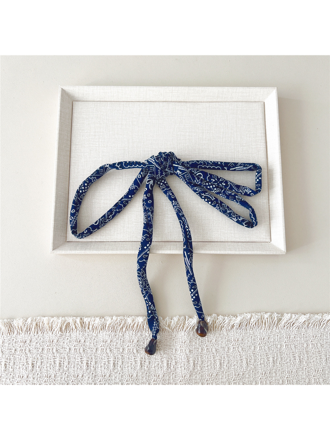 Navy paisley skinny scarf tied in a wide bow