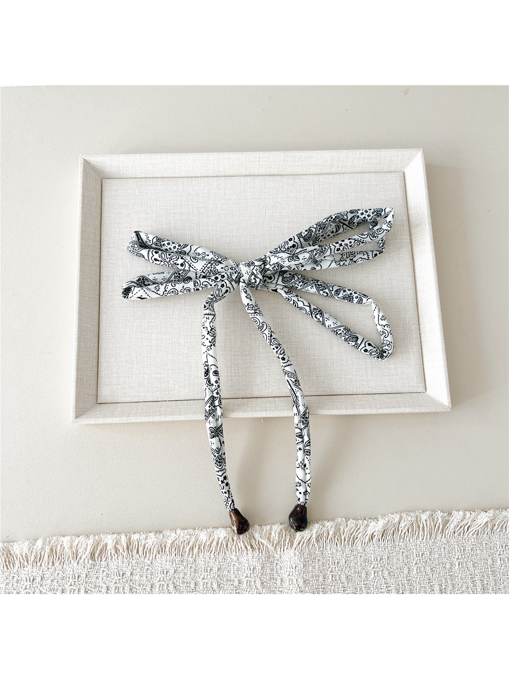 White paisley skinny scarf tied in a wide bow